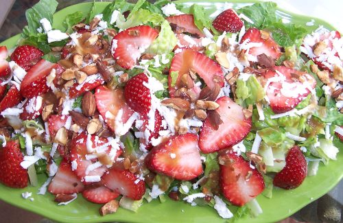 Strawberries and grated feta cheese on a bed of greens