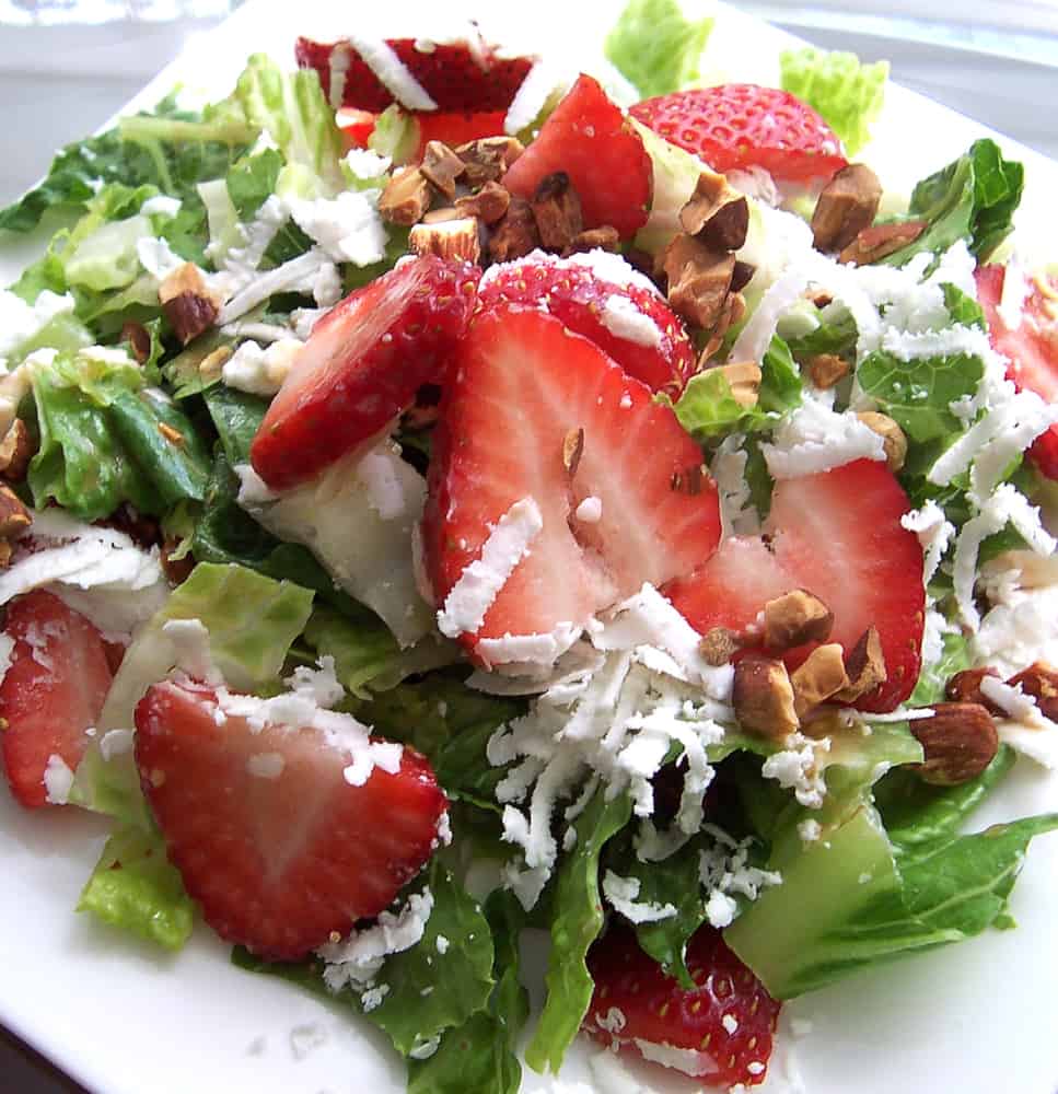 Strawberries on a bed of greens drizzled with creamy garlic dressing