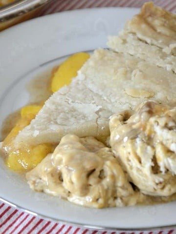 Slice of peach pie on a plate with Dulce de Leche ice cream on the side..
