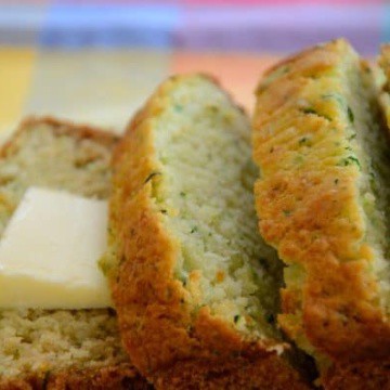 Sliced loaf of savory zucchini loaf with a pat of butter.