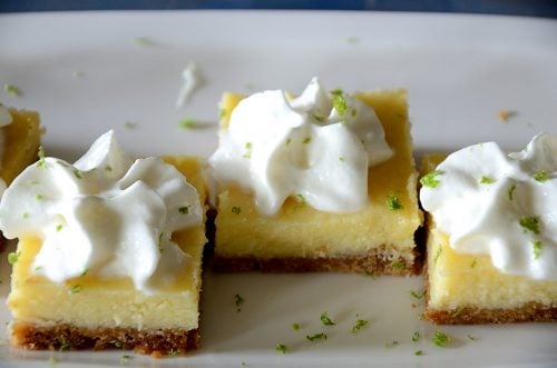 Tequila lime squares topped with whipped cream on a plate.