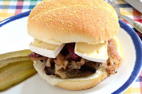 Burger with onions and brie on a plate.