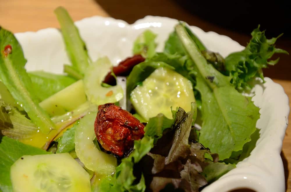 Mixed lettuce greens in with roasted tomatoes and cucumbers.