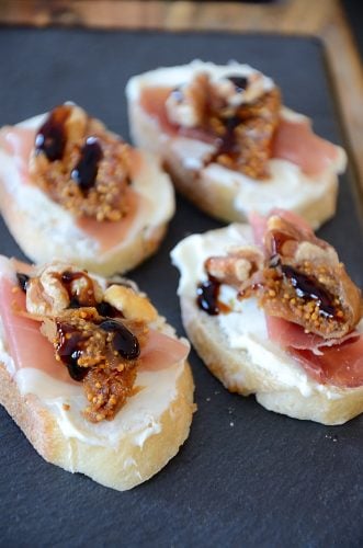 Crostini with cream cheese, serrano ham, fig and walnut on a slate tray