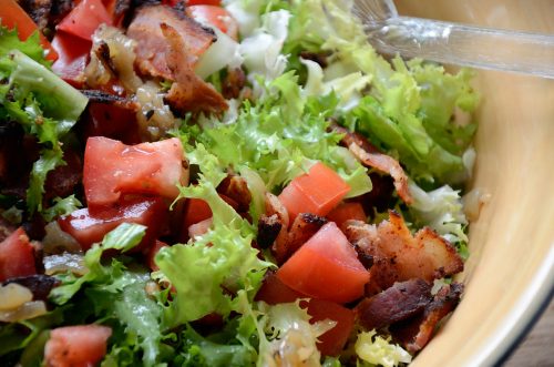 Close up of salad with escarole, bacon and tomato in a bowl