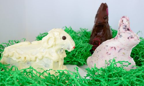 White iced lamb cake and frozen yogurt bunny mold sitting in Easter grass.