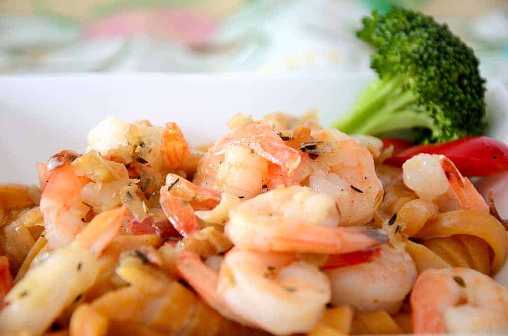 Close up of jumbo shrimp over pasta with a creamy sauce.