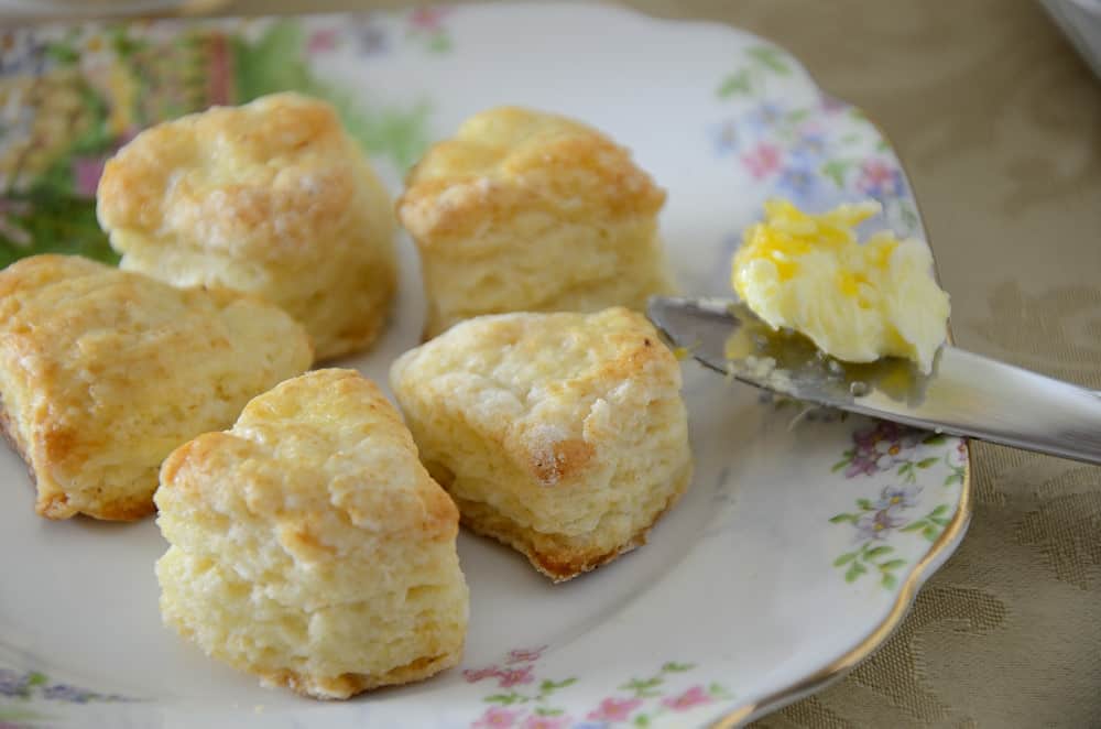 Tiny heart shaped scones with mandarin butter on a tea plate.