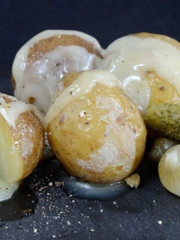 Baby potatoes with raclette cheese melted over them and garnished with gherkins and cocktail onions.