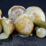 Baby potatoes with raclette cheese melted over them and garnished with gherkins and cocktail onions.