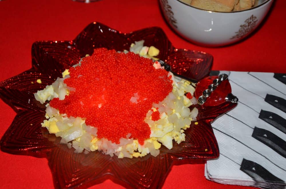 Christamas star plate with chopped hard boiled egg, topped with sweet onions diced finely and red caviar.