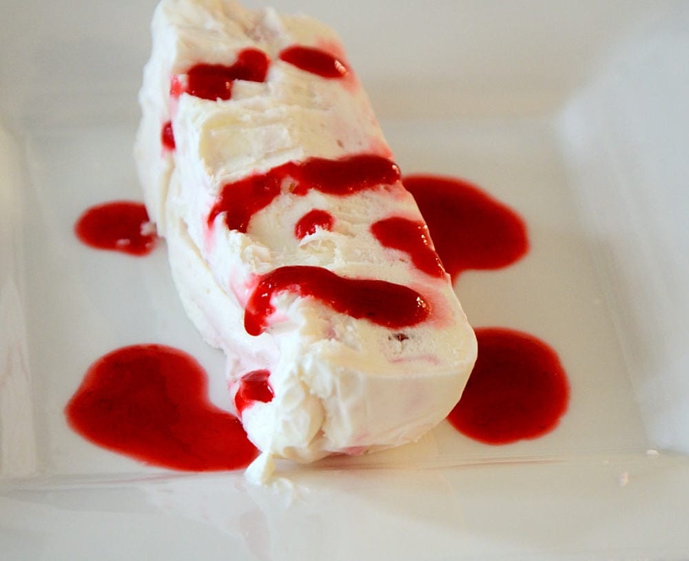 Serving of Limoncello Semifreddo with raspberry coulis.