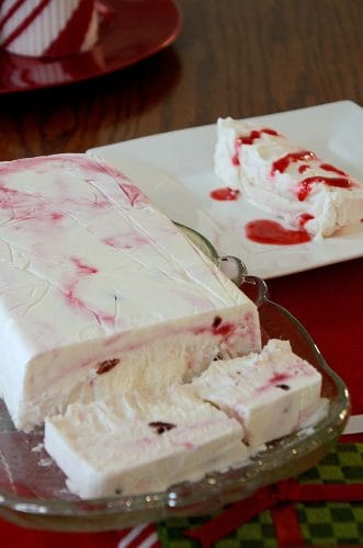 Limoncello Raspberry Semifreddo slice plated with raspberry coulis