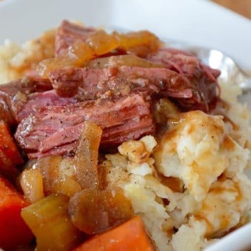 Brisket in Guinness gravy with carrots and celery in a bowl over Colcannon