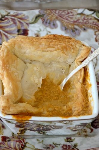 Spoon in square soup bowl, broken through puff pastry to lobster bisque