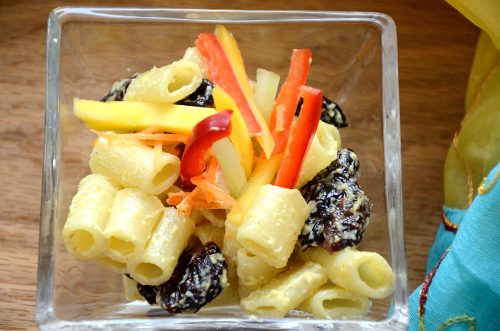 Bombay Pasta salad in a dish with mango and red pepper garnish
