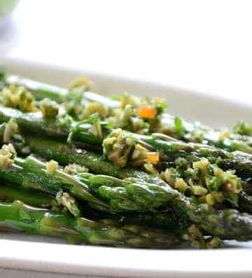 Asparagus spears on serving plate sprinkled with olive gremolata