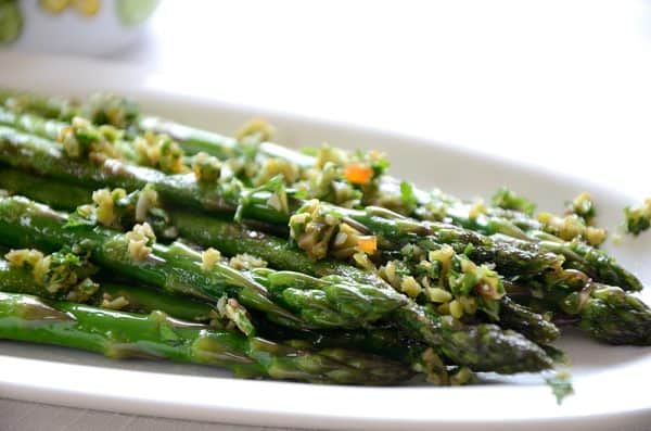 Asparagus spears on serving plate sprinkled with olive gremolata