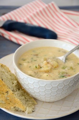 Bowl of creamy scallop chowder with dill bread on the side