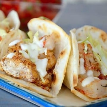 Three grilled shrimp tacos with lime crema garnish