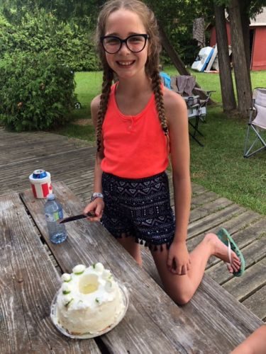 Proud young girl with Lime cake on picnic table