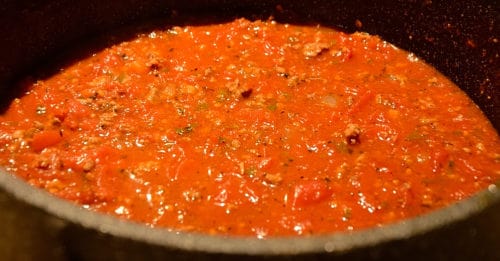 A pot of spaghetti sauce simmering on a stove
