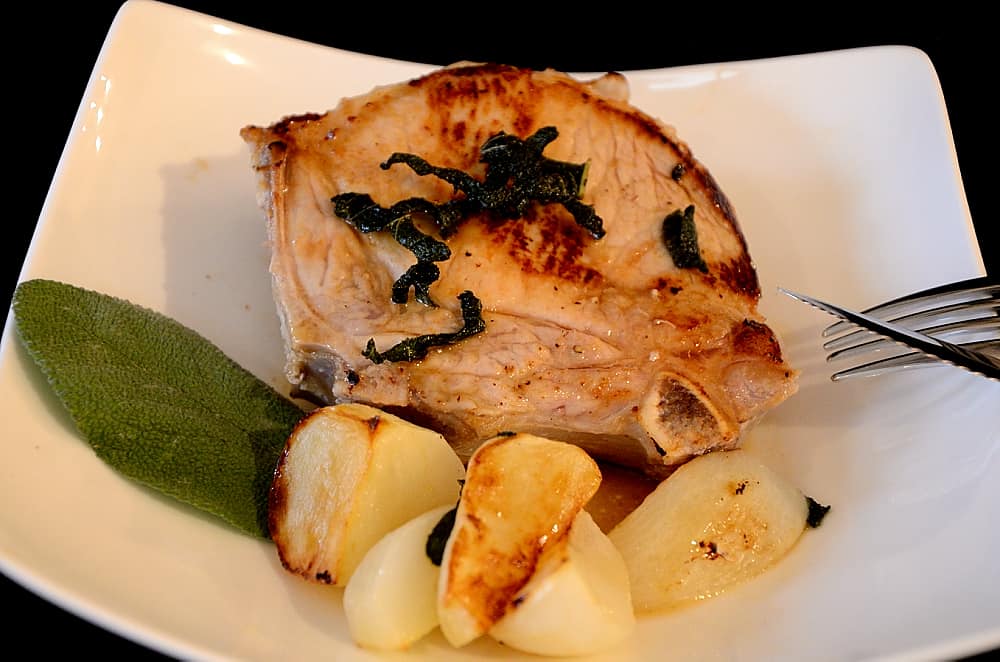 Pork chop on a plate with glazed turnips.