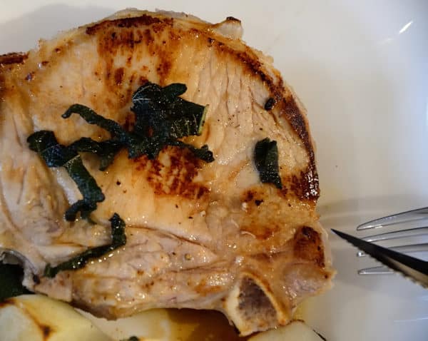 Grilled pork chop with sage butter garnish on a plate