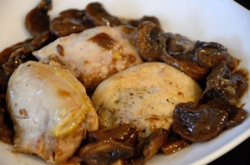 Three chicken thighs in a bowl with balsamic mushroom sauce