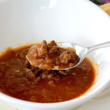 Bowl of goulash soup with a spoonful of broth and beef chunks.