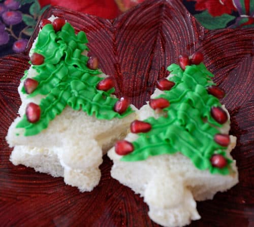 Christmas tree shaped sandwich with green cream cheese icing and pomegranate decorations