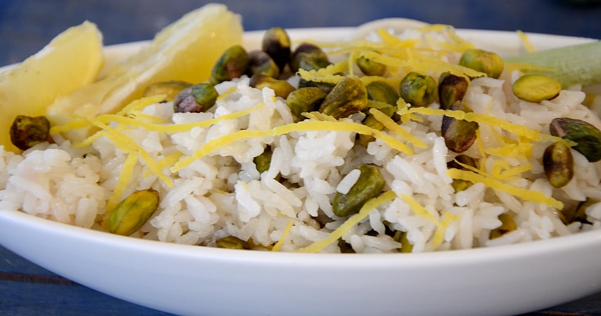 Platter of rice with lemon twists and pistachios garnished with fresh lemon