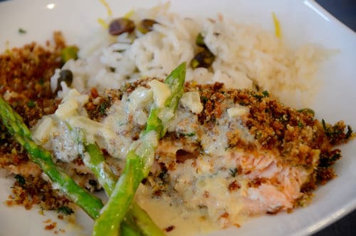 A plate with Herb crusted salmon beside Lemon Pistachio rice sauced with Lemon Cream