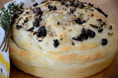 Round loaf of bread with black olives and onions on top