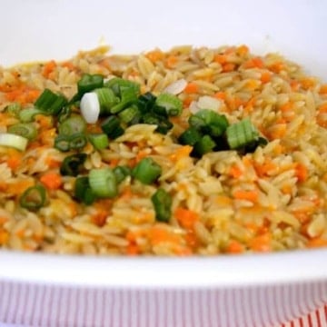 bowl of carrot orzo with green onion garnish