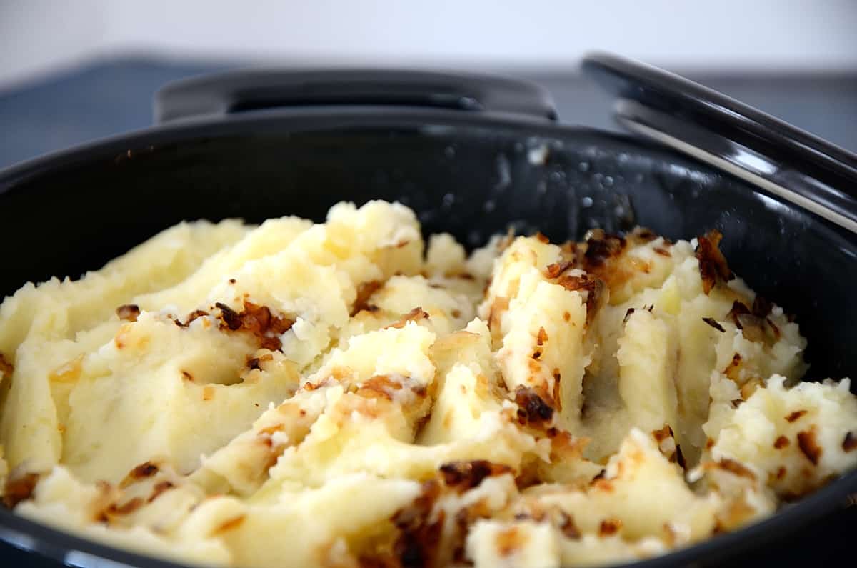 A casserole filled with mashed potatoes and golden caramelized shallots.