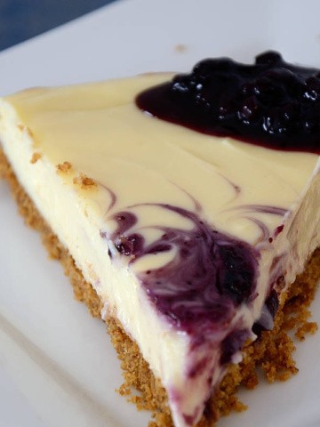 Slice of blueberry cheescake on a plate with a dollop of blueberry jam