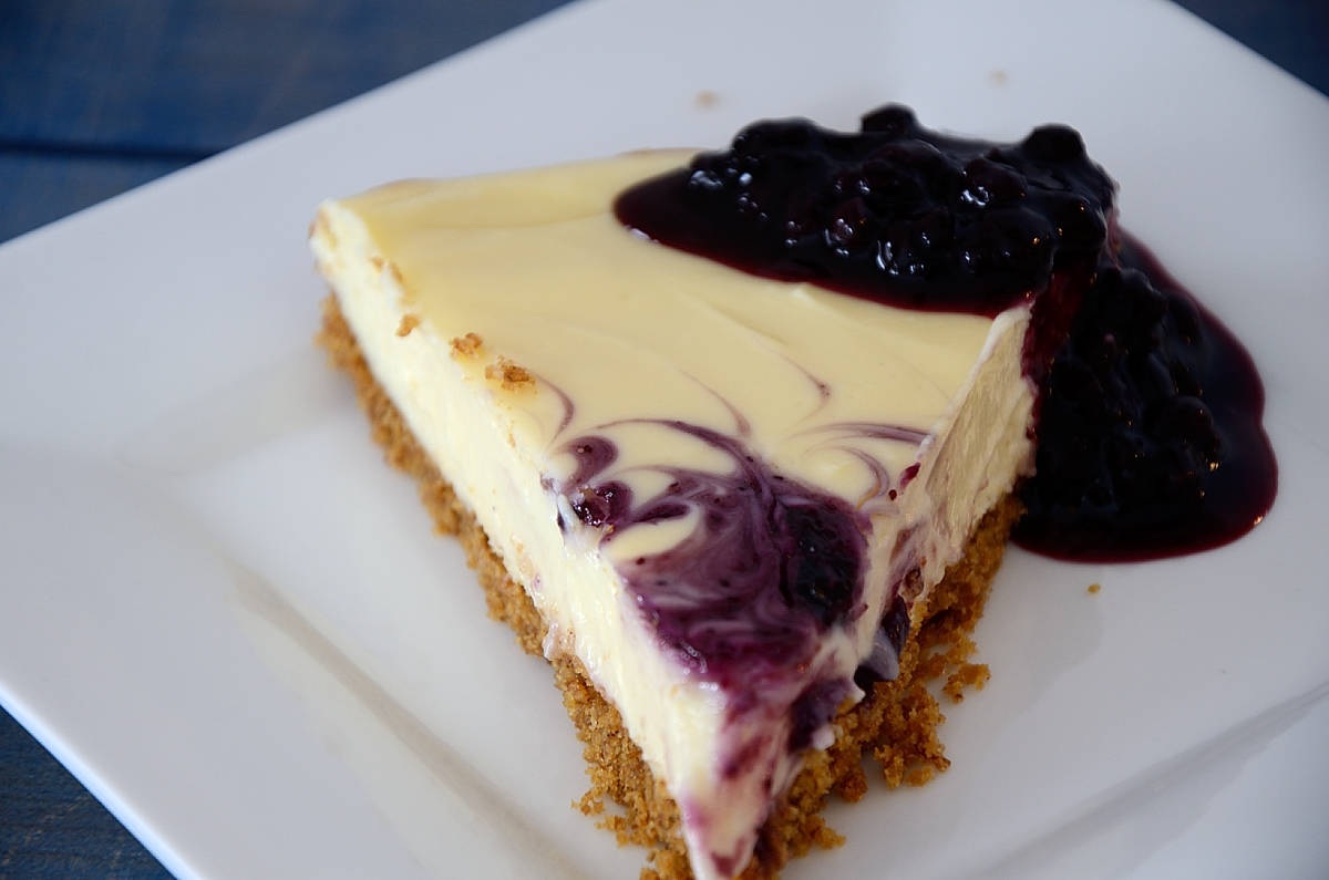 Slice of blueberry cheescake on a plate with a dollop of blueberry jam