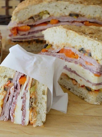 Wedges of muffuletta sandwich wrapped in parchment paper.