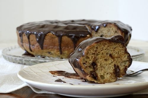 Glazed chocolate banana bundt cake with one piece cut on a serving plate