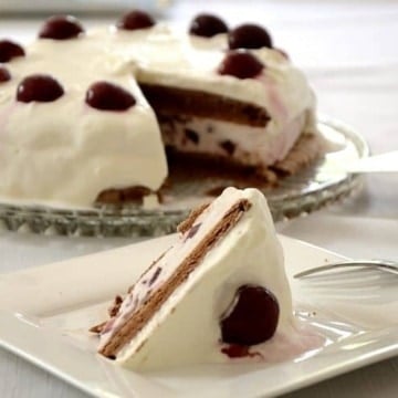 Chocolate meringue layers with black cherry ice cream filling and whipped cream frosting. Decorated with black cherries.