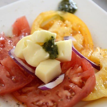 Heirloom tomato slices topped with dressing, cheese and pesto.