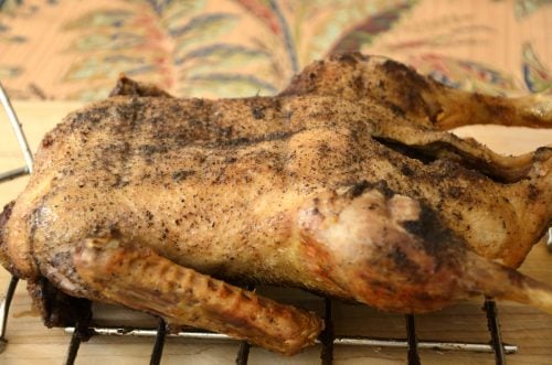 Crispy roasted duck on a wire rack with cinnamon seasoning rubbed on skin.