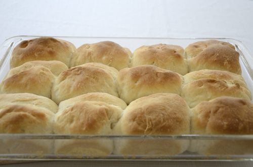 Golden brown baked Parker house rolls in baking pan.