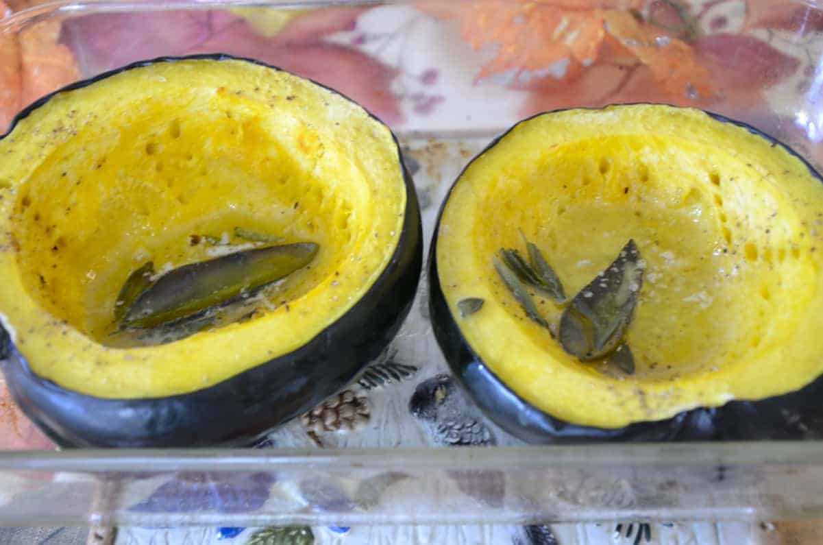 Two roasted acorn squash halves with butter and sage.