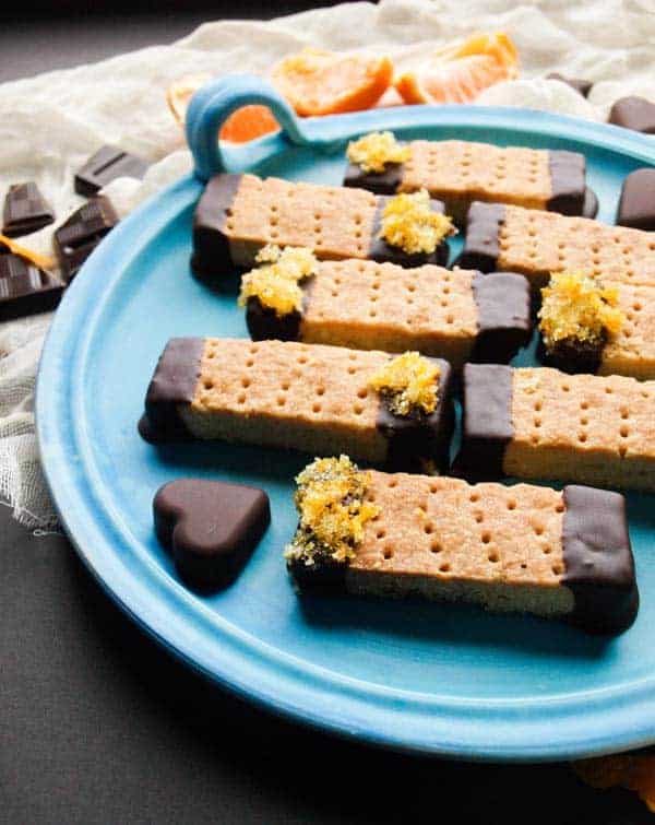 Plate of rectangular Scottish shortbread biscuits dipped in chocolate with oranze zest.