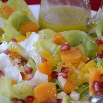 Salad on a platter with persimmons, mandarins and pomegranate seeds.