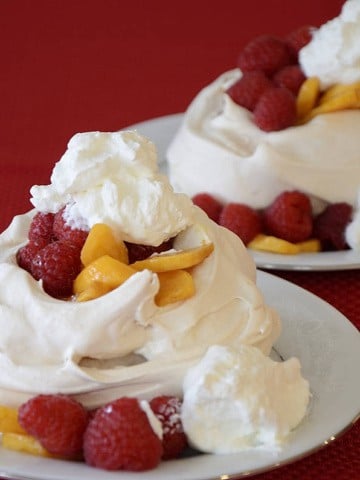 Two pavlovas on dessert plates.