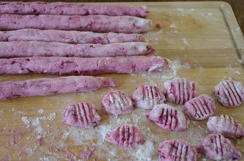 Beet gnocchi on a work surface with fork marks etched into gnocchi.