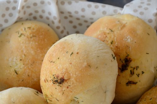 Basket of round buns with dill fronds brushed on the surface.